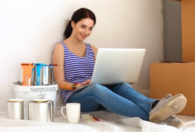 Yeni daire dizüstü bilgisayar ile oturup, boyama sırasında genç kadın portre