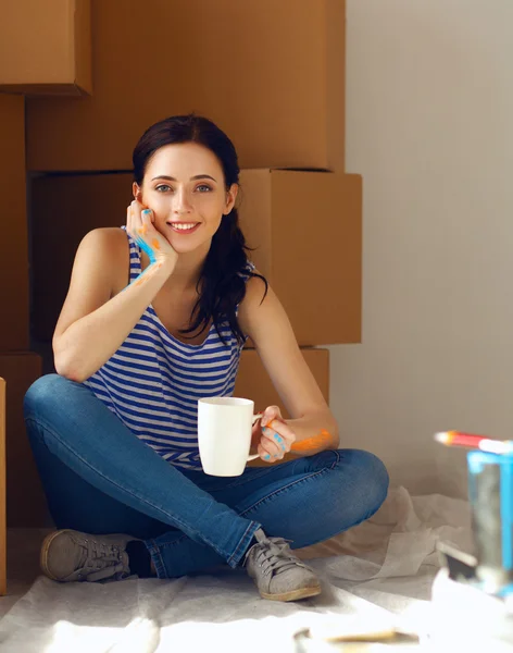 Vrouw verf kleur kiezen uit staal voor nieuwe huis zittend op houten vloer — Stockfoto