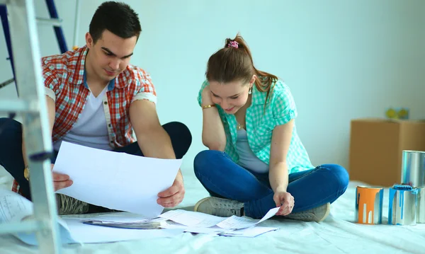 Pareja joven sentada en el suelo y calculando sobre sus ahorros — Foto de Stock