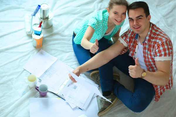 Junges Paar sitzt auf dem Boden und rechnet über seine Ersparnisse — Stockfoto