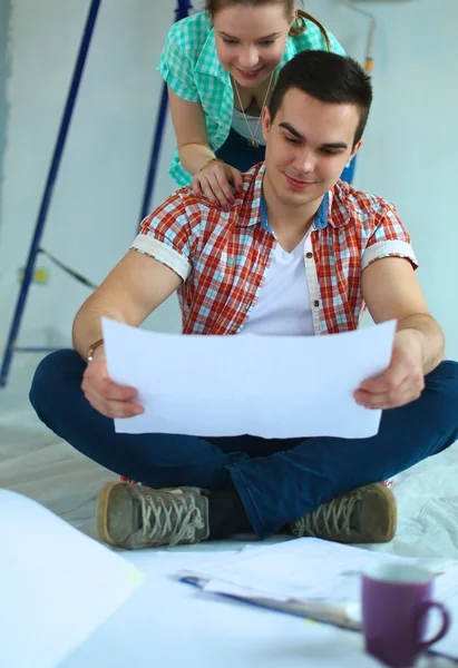 Pareja joven sentada en el suelo y calculando sobre sus ahorros —  Fotos de Stock