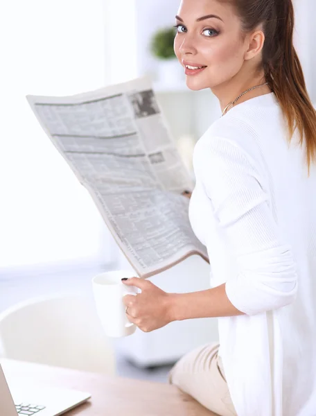 Cute businesswoman holding newspaper sitting at her desk in office — Stock Photo, Image