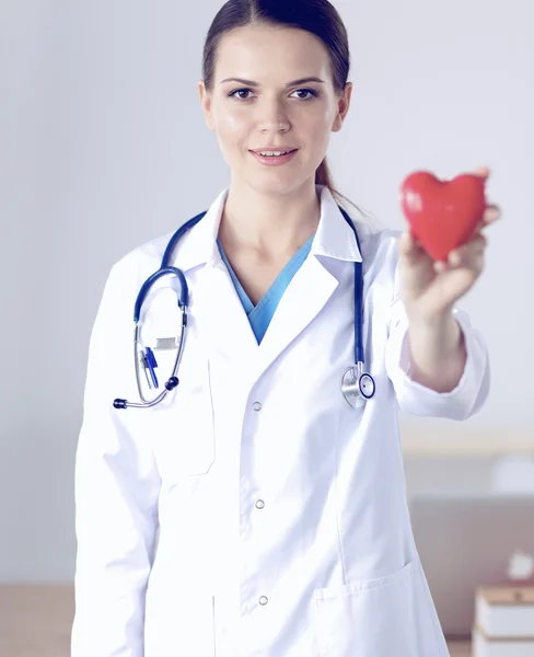 Mladá žena lékař drží červené srdce, izolované na bílém pozadí — Stock fotografie
