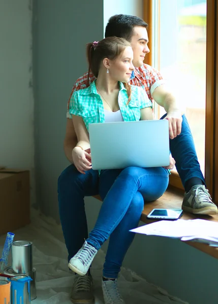 搬进新家坐在一起的笔记本电脑对年轻夫妇的肖像 — 图库照片
