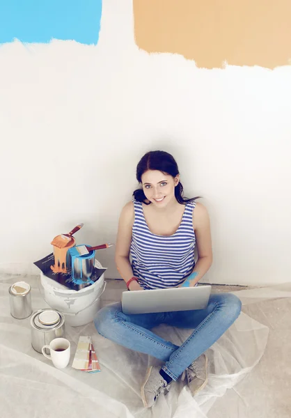 Portrét mladé ženy při malování nový byt, sedí s notebookem — Stock fotografie