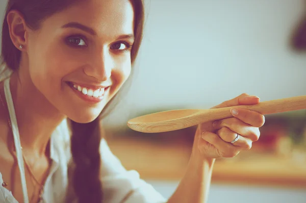 Cooking woman in kitchen with wooden spoon — Stock Photo, Image