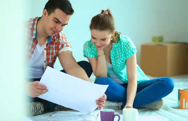 Ungt par sitter på golvet och beräkna om de besparingar — Stockfoto