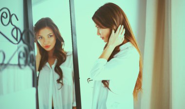 Genç kadın kendini evde aynada yansıma arıyor