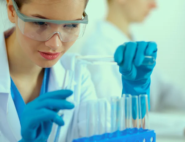 Woman researcher is surrounded by medical vials and flasks, isolated on white background — Stock Photo, Image