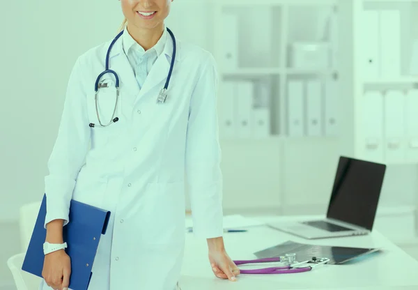 Smiling female doctor with a folder in uniform standing at hospital — Stock Photo, Image