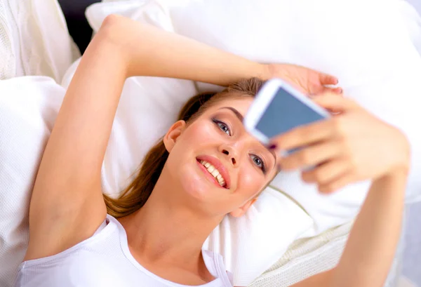 Morena feliz tomando una foto de sí misma con su teléfono móvil en el dormitorio —  Fotos de Stock
