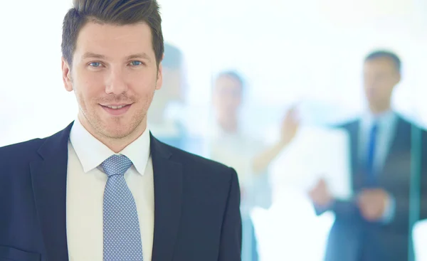 Portret van jonge zakenman in kantoor met collega's op de achtergrond — Stockfoto