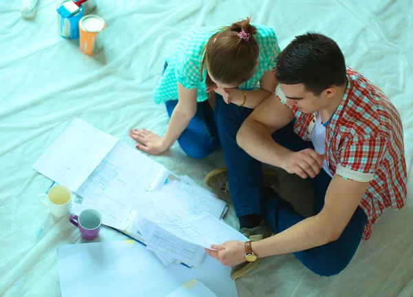 Junges Paar sitzt auf dem Boden und rechnet über seine Ersparnisse — Stockfoto