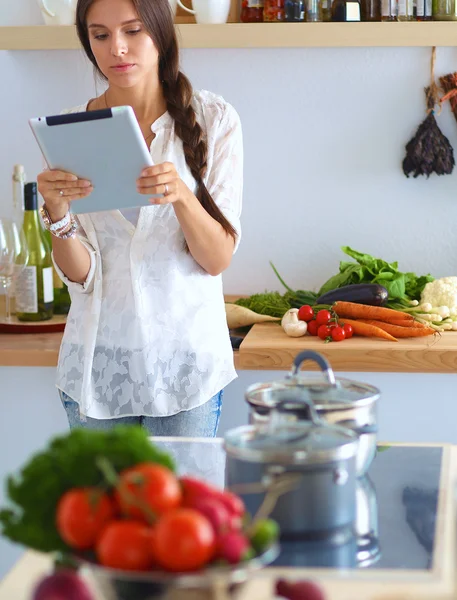 Junge Frau kocht mit Tablet-Computer in ihrer Küche — Stockfoto