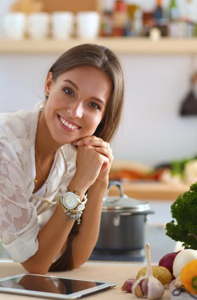 Jeune femme utilisant une tablette informatique pour cuisiner dans sa cuisine — Photo