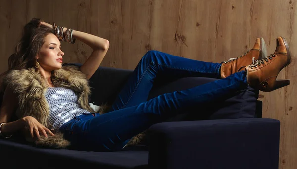 Retrato de una mujer elegante sentada en un sofá negro con un azul — Foto de Stock