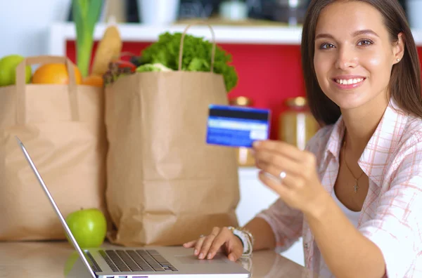 Femme souriante achats en ligne en utilisant tablette et carte de crédit dans la cuisine — Photo