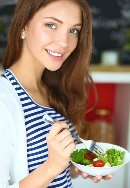 Mujer joven comiendo ensalada y sosteniendo una ensalada mixta — Foto de Stock