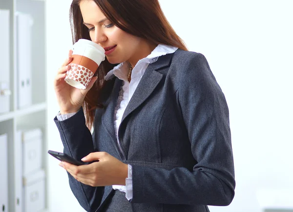 Attractive young businesswoman standing near desk with folder in the office — Stock Photo, Image