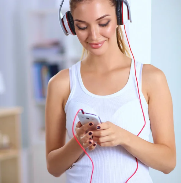 Kvinna med hörlurar lyssnar musik stående hemma — Stockfoto
