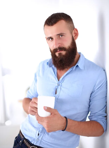 Jonge man permanent in de buurt van muur en houden kopje koffie — Stockfoto