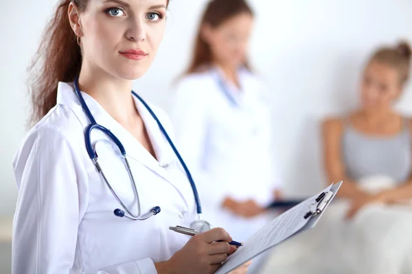 Sorridente medico donna con una cartella in uniforme in piedi in ospedale — Foto Stock