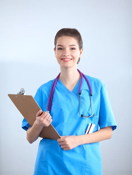 Médico sonriente con una carpeta en uniforme de pie en el hospital — Foto de Stock