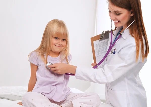 Female doctor examining child with stethoscope at surgery. Stock Picture