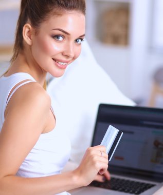 Kadın kredi kartı ve bilgisayarla online alışveriş yapıyor.