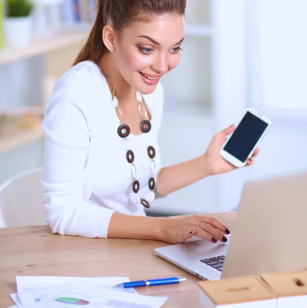 Joven mujer de negocios sentada en el escritorio y hablando por teléfono — Foto de Stock