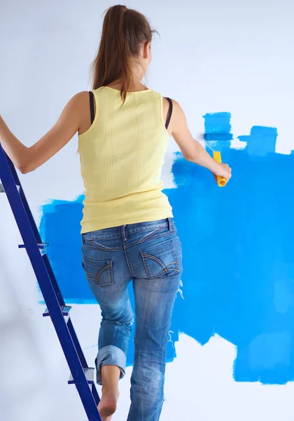 Feliz hermosa mujer joven haciendo pintura de pared, de pie en la escalera — Foto de Stock