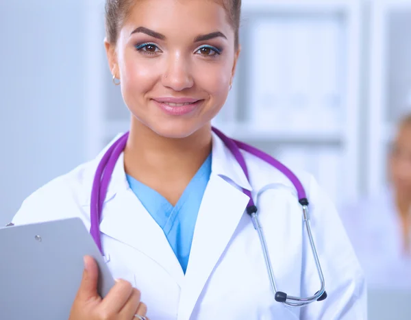 Sorridente medico donna con una cartella in uniforme in piedi in ospedale — Foto Stock