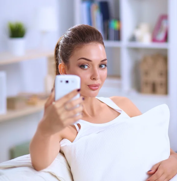 Morena feliz tomando una foto de sí misma con su teléfono móvil en el dormitorio —  Fotos de Stock