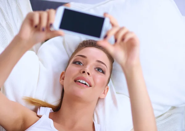 Morena feliz tomando una foto de sí misma con su teléfono móvil en el dormitorio —  Fotos de Stock
