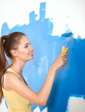 Mutlu güzel bir kadın duvar boyuyor.