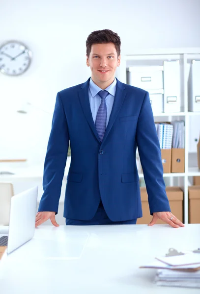 Podnikatel nebo manažer stojí u svého stolu v kanceláři — Stock fotografie