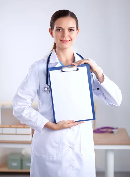 Médico sonriente con una carpeta en uniforme de pie en el hospital — Foto de Stock