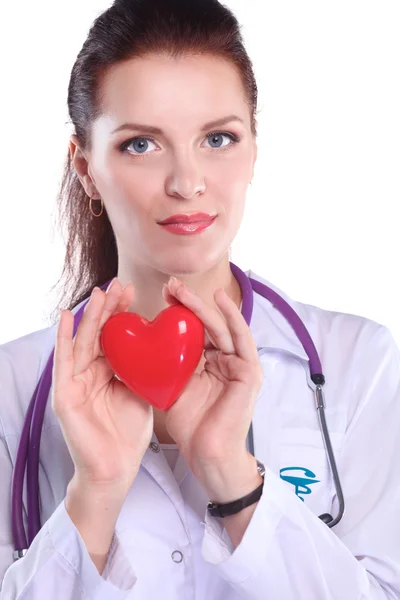 Νεαρή γυναίκα γιατρός κρατώντας μια κόκκινη καρδιά, στέκεται σε γκρι φόντο — Φωτογραφία Αρχείου