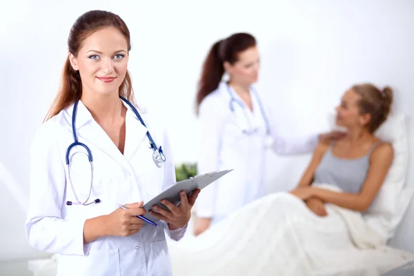 Sorridente medico donna con una cartella in uniforme in piedi in ospedale — Foto Stock