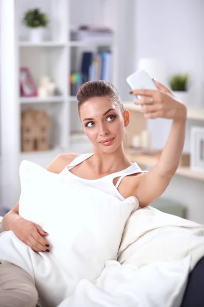 Morena feliz tomando una foto de sí misma con su teléfono móvil en el dormitorio —  Fotos de Stock