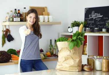 Elinde sebzeli alışveriş torbası tutan genç bir kadın.