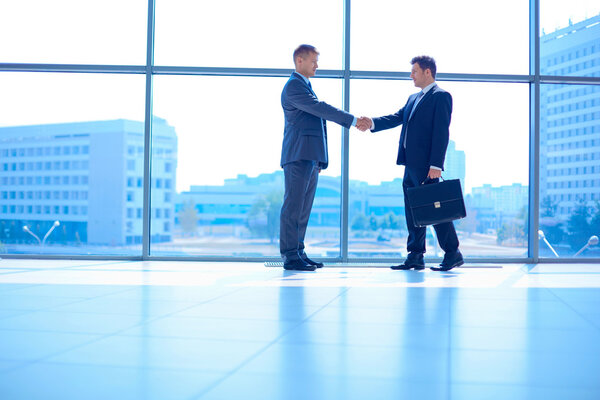 Full length image of two successful business men shaking hands with each other