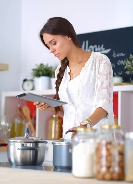 Mujer joven usando una tableta para cocinar en su cocina —  Fotos de Stock