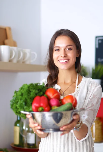 Sorridente giovane donna che tiene le verdure in piedi in cucina — Foto Stock