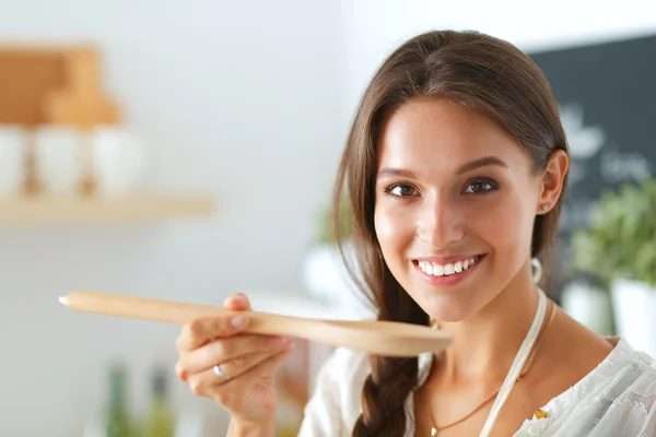 Mujer cocinera en cocina con cuchara de madera —  Fotos de Stock