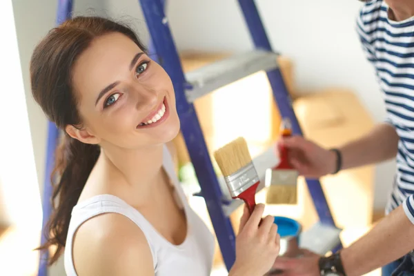 Retrato de feliz joven pareja sonriente pintando la pared interior de la nueva casa —  Fotos de Stock