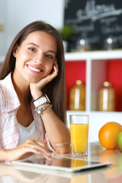 Donna che usa un tablet mentre beve tè nella sua cucina — Foto Stock