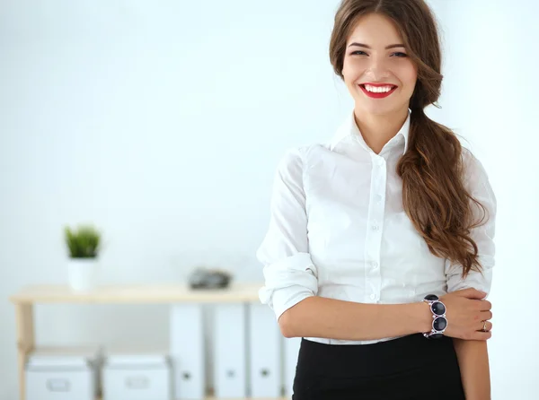 Attractive businesswoman standing near wall in office — Stock Photo, Image