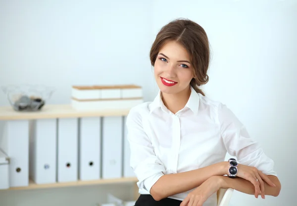 Attractive businesswoman standing near wall in office — Stock Photo, Image