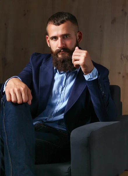 Affärsman som sitter i soffan i kontoret lobbyn, isolerad på mörk bakgrund — Stockfoto